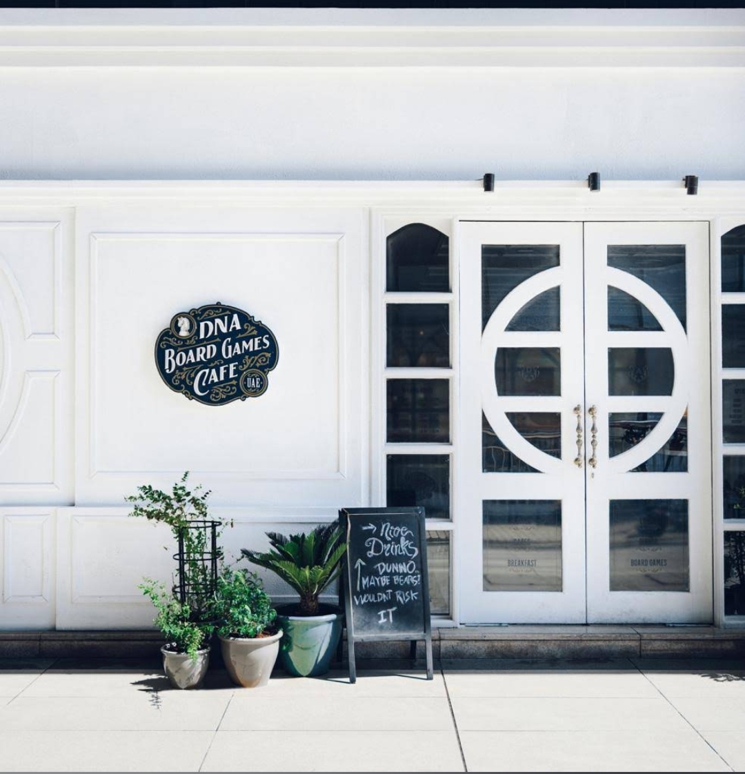 DNA Board Games Cafe storefront with white doors and potted plants