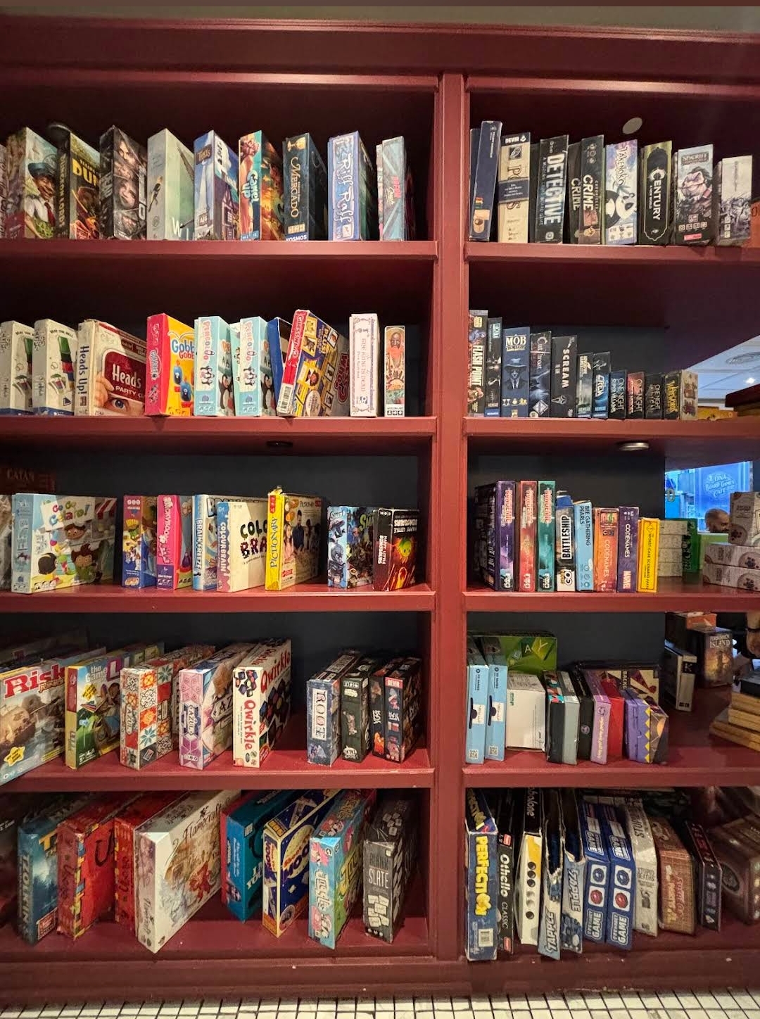 Wall of board games on red wooden shelves inside DNA